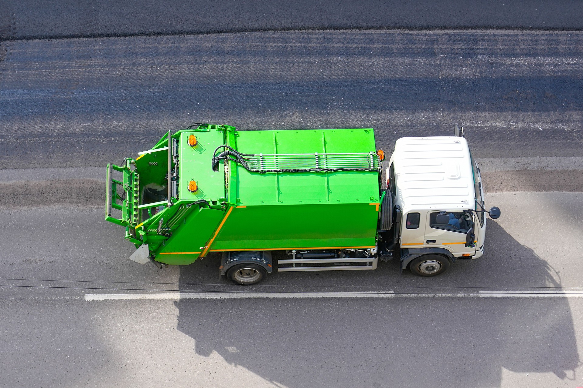 Recycling truck rides on the road in the city, aerial top view